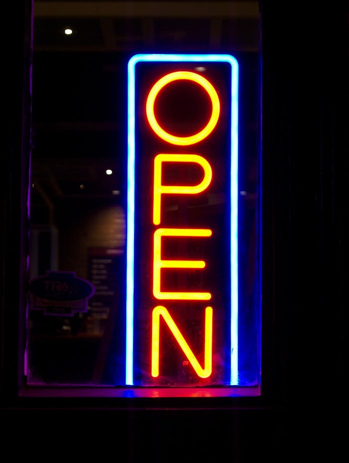 services-03 Illuminated neon sign displaying 'OPEN' with vibrant colors at night.