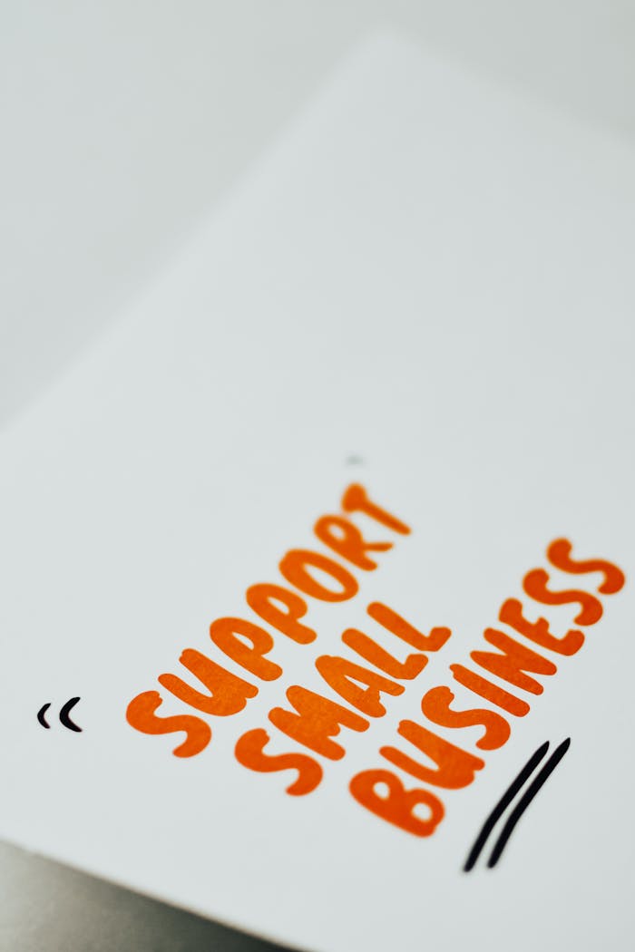 contact-bg Close-up of a 'Support Small Business' message in orange text on a white paper.